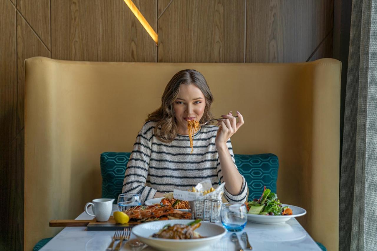 Pullman Sharjah Hotel Exterior foto A woman eating at a restaurant